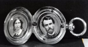 An open locket with a picture of a Victorian woman on the left side and a man on the right