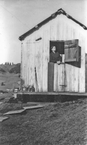 A woman in a small wooden building looking up at the sky