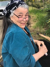 Woman with glasses wearing a blue shirt and a black and white bandana tied around her long hair