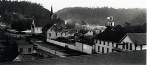 Elevated view of buildings and streets, with hills and trees in the background