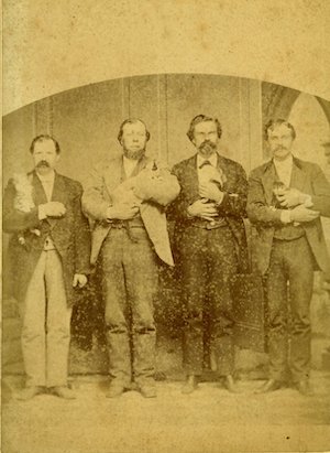 Four men in suits holding cats or dogs