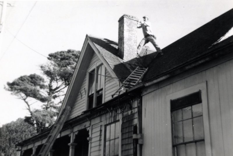 Man stands on roof, repairing chimney
