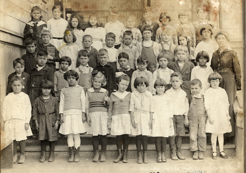 Young children standing in 4 rows on school steps, facing camera