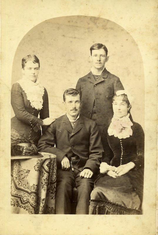 Man and woman standing behind a man and woman, who are seated