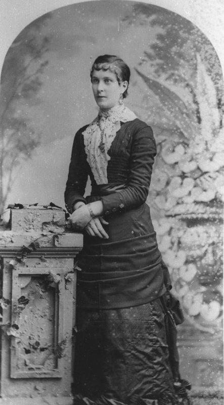 Woman in long dress leans on podium