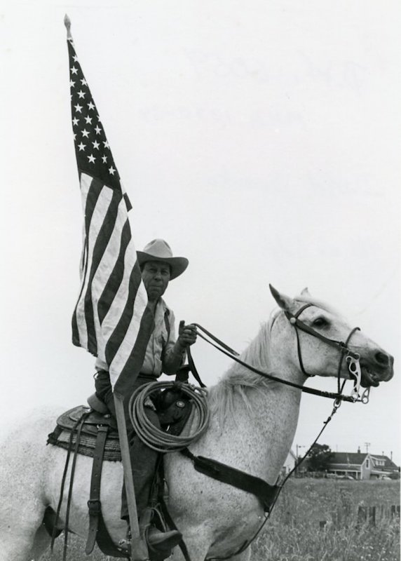 Man on horseback, waving a large American Flag