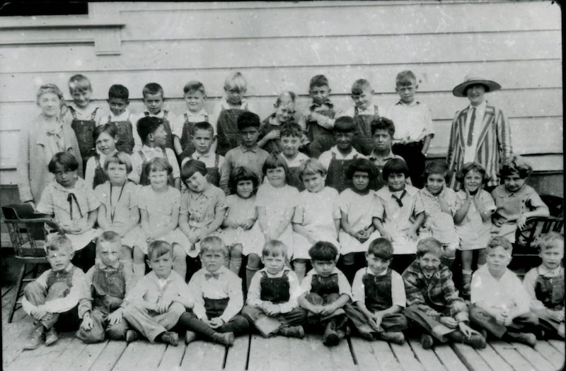 Young children sitting in rows on steps facing camera
