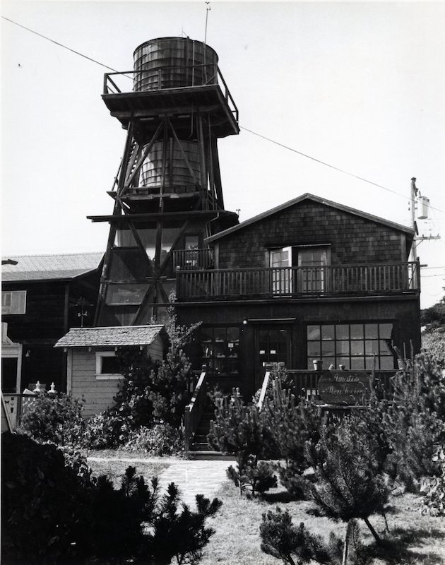 Looking uphill towards commercial buildings. A two-tank water tower towers over the shops