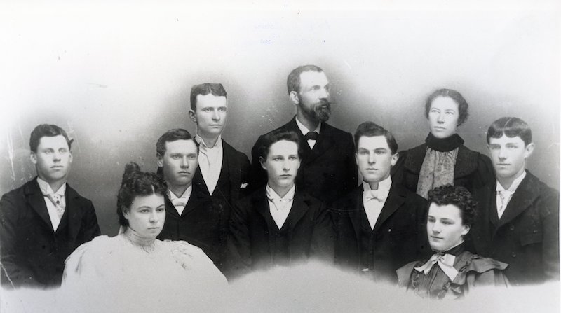 Studio portrait of teachers standing behind seven graduating high school seniors