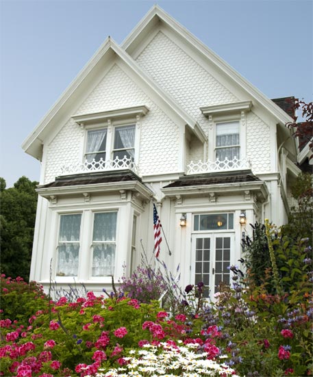 white Victorian two story house with roses in front