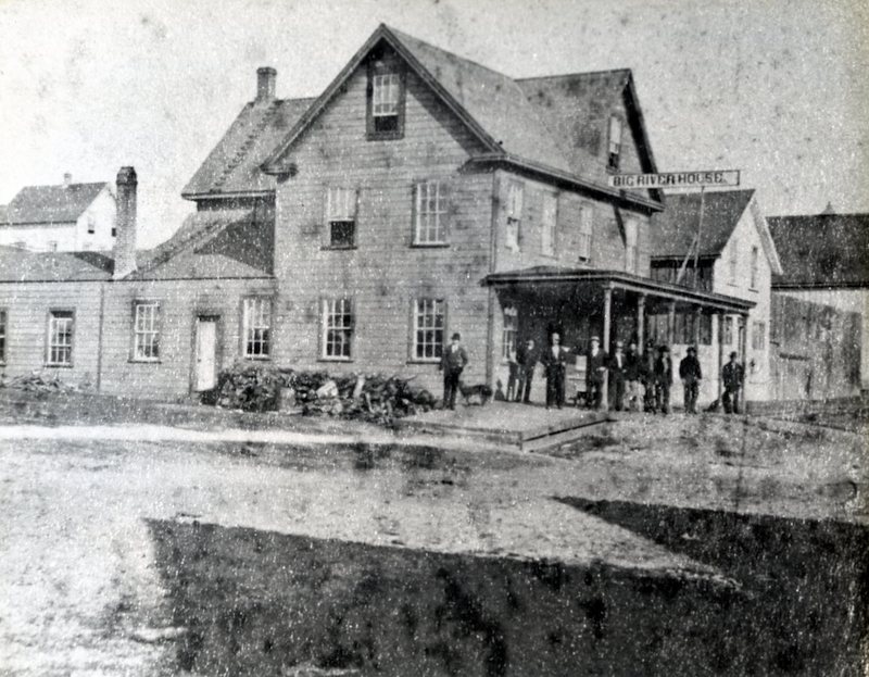 Large Hotel Building. A group of men are posing in the front.