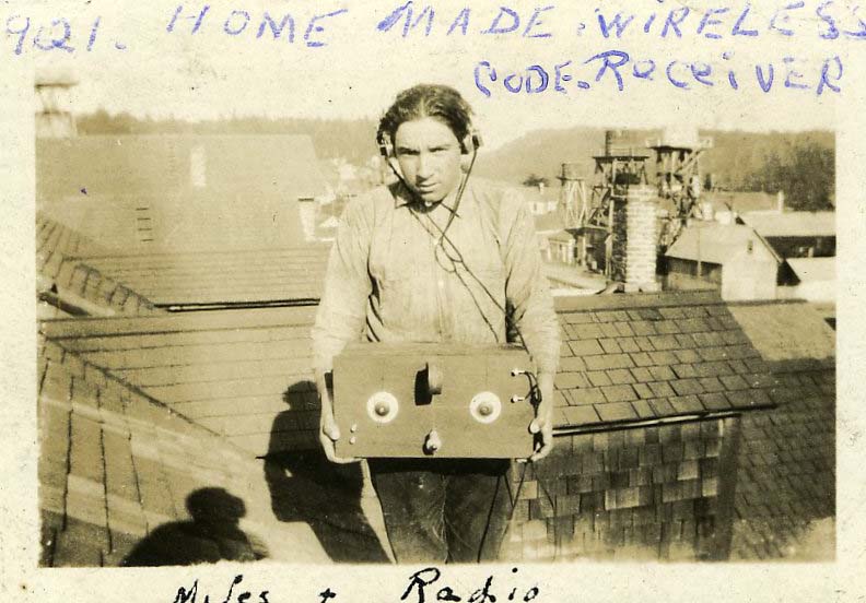 Boy wearing headphones standing on roof holding large radio