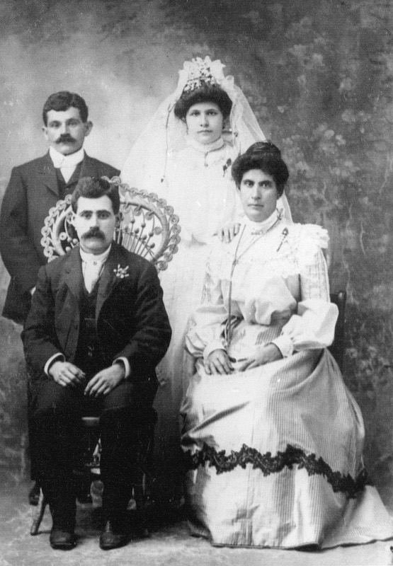 Young couple standing behind a seated older couple