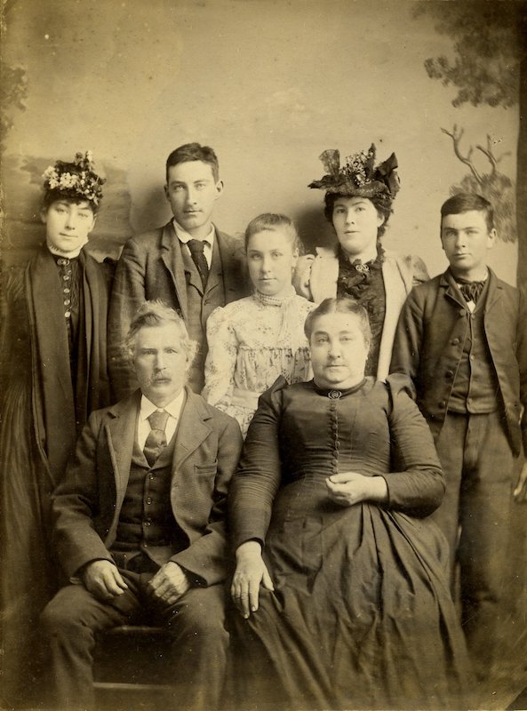 Studio Portrait. Older couple seated, five young adults stand behind them
