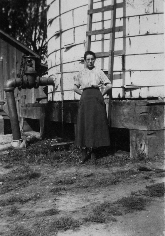 Woman standing in front of large water tank with ladder