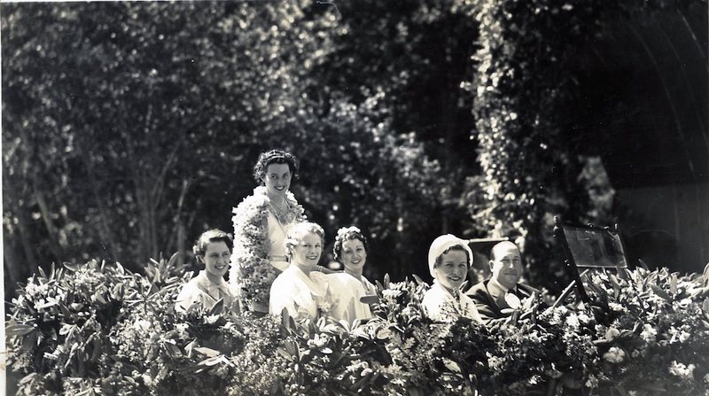 Five women and a man in a decorated parade car