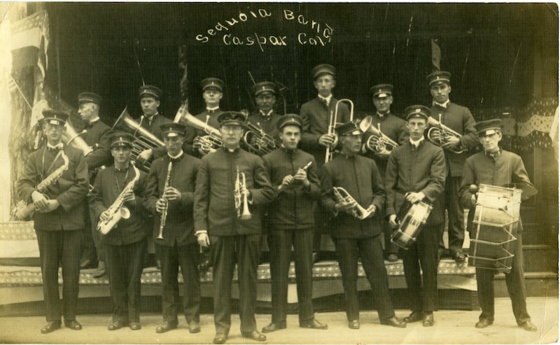 Group of young men in band uniforms carrying musical instruments