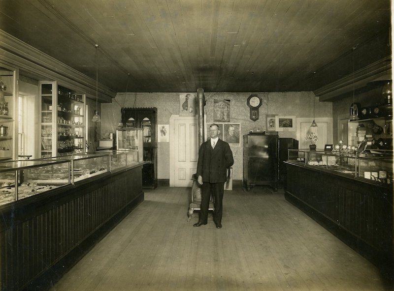 Interior of a jewelry store with a man in a suit standing in the center of the photo