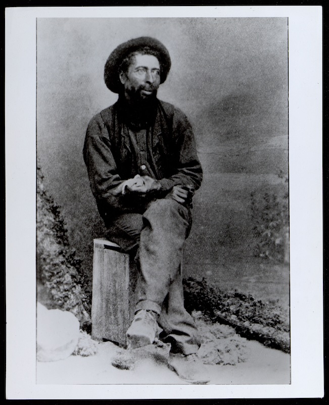 Man in hat sitting on bench with legs crossed