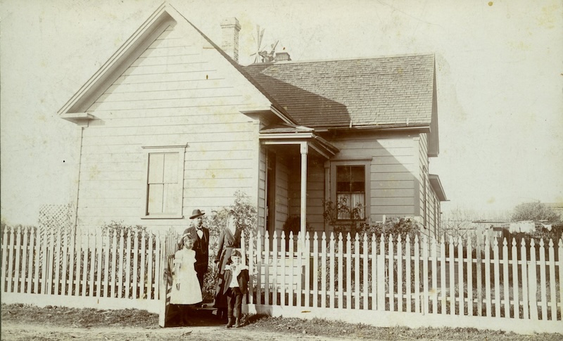 Family of four posing in front of historic home