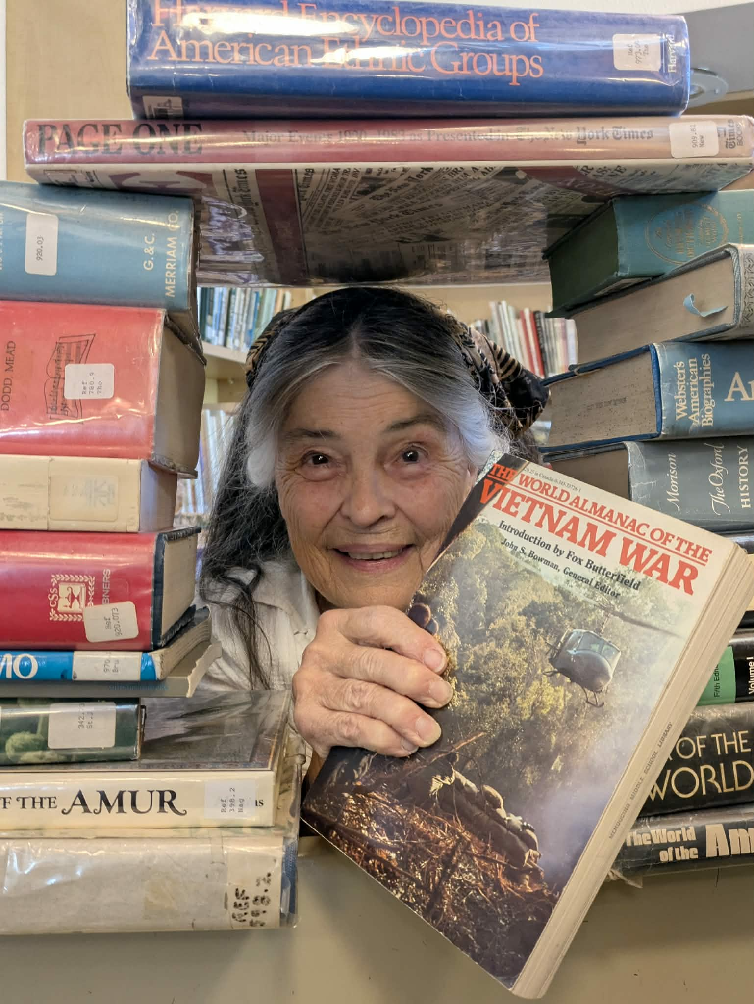 woman holding a book next to a stack of books