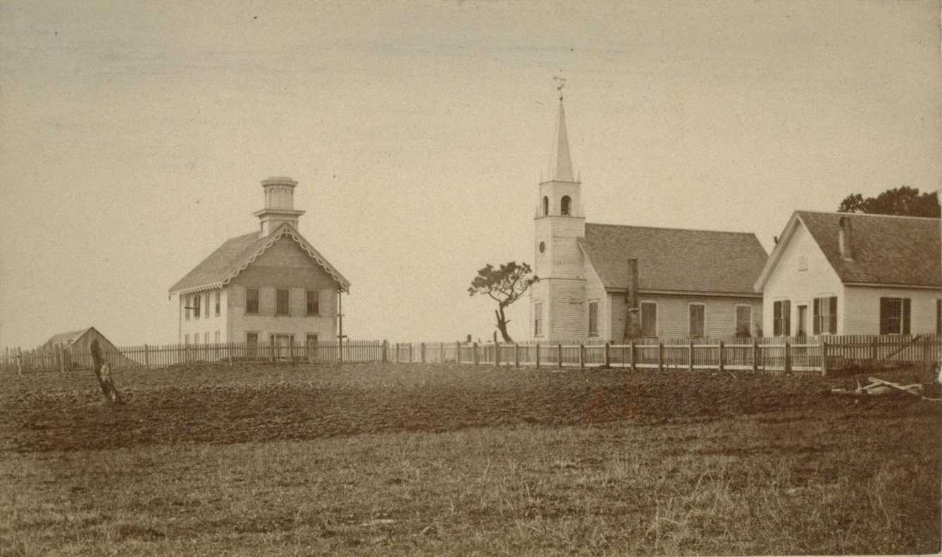 Three historical buildings stand on the other side of an open field