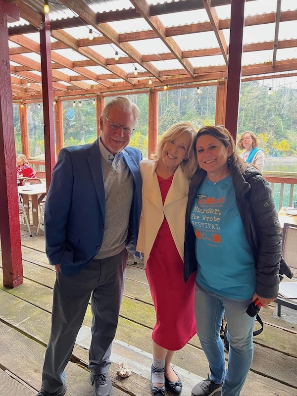 Man and two women pose together facing camera