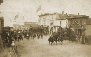 Horse-back riders and marchers carrying flags and banners march toward the camera