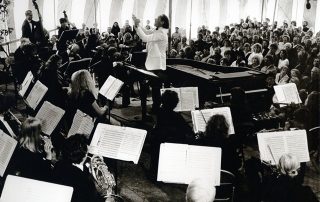 Man conducts orchestra in circus tent
