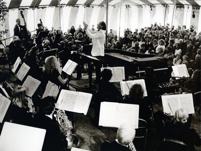 Man conducts orchestra in circus tent