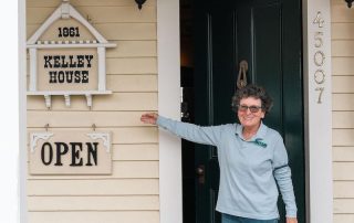 Woman pointing at Open sign in front of Kelley House Museum