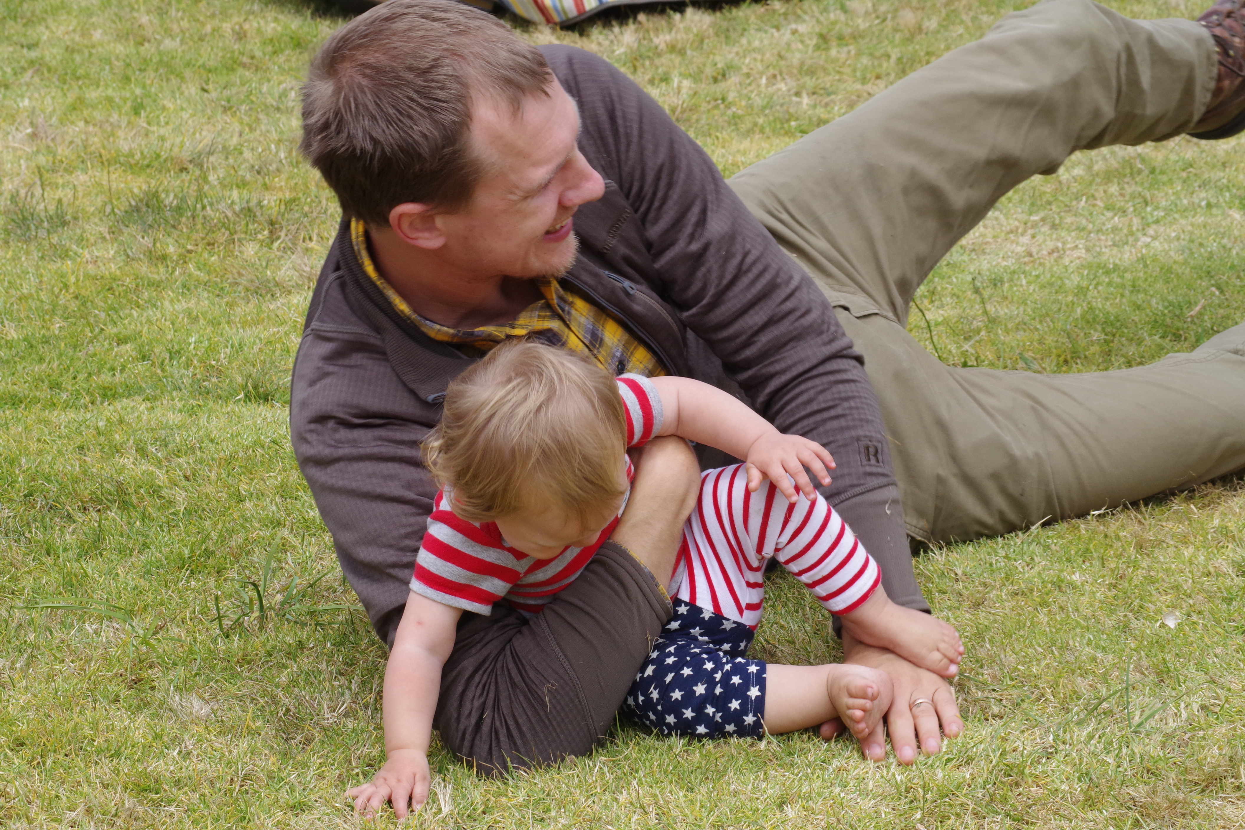Man and child in American flag outfit playing in the grass