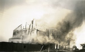 A building on fire, with the building frame exposed and billowing smoke