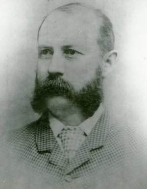 Portrait of a Victorian man in a checked suit and tie with mustache and mutton chops
