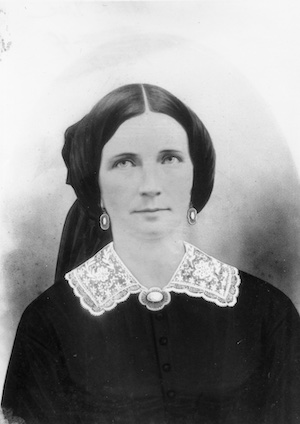 Studio portrait of a Victorian woman wearing earrings, a brooch and lace collar
