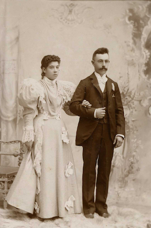 Studio portrait of a well-dressed, late Victorian era couple standing arm in arm