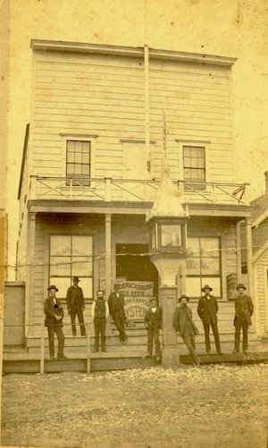 Men in suits standing outside a building with a large light on a column in front