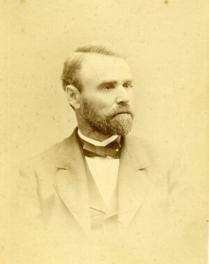 Studio portrait of a bearded man in a suit looking off to the side