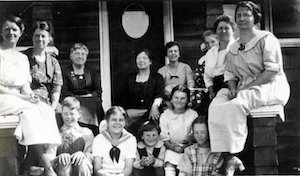 Group of women and children posing outside a home