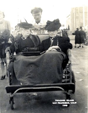 Two elderly women with blankets over their legs in a bike taxi driven by a man