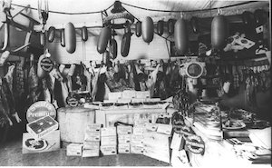 Interior of a shop with goods on a table and meats hanging from ropes