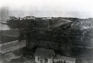 Aerial view of a town with buildings and streets leading out to a promontory over the water