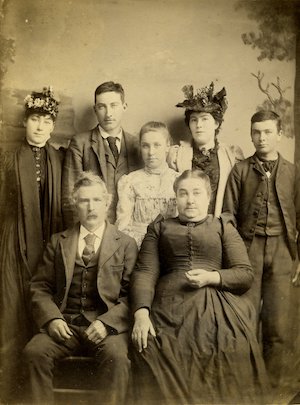 Family of seven sitting and standing while posing for a studio portrait 