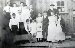 Large family of various ages standing in front of building