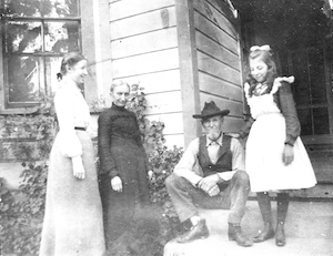 Family of four posing in front a house