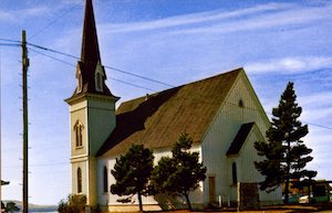 Color photograph of a white church with trees in front