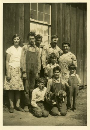 Family photo of parents, seven children of assorted ages and two pets in front of a house