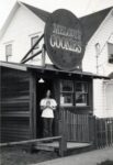 Denny Greenberg standing in the doorway of Melody's Cookies, a store located on Lansing Street just south of Little Lake Street, April 1975. The “Melody’s Cookies” sign was created by John Chamberlin.