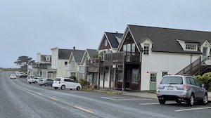 Street lined with two-story buildings and cars parked in front