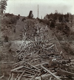 Jughandle trestle in Caspar after the earthquake of 1906. Image shows the bridge completely destroyed with a section of railroad track lying on a pile of wood. Photograph was taken as two images and glued together on a board. (Gift of Emery Escola, Emery Escola Collection, Kelley House Photographs)